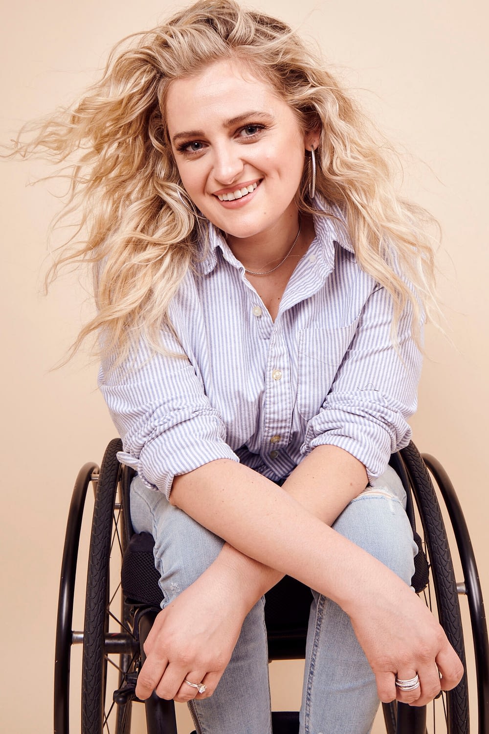 Ali smiles with her arms crossed while sitting in her wheelchair.