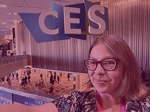 A selfie photo of Kat Zigmont in front of a large "CES" billboard.