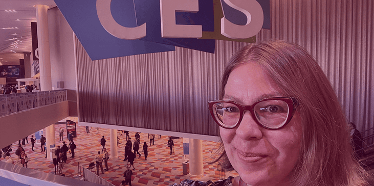 A selfie photo of Kat Zigmont in front of a large "CES" billboard.