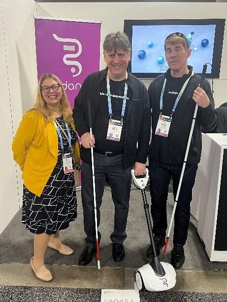 Kat Zigmont smiling with two blind Glidance team members, both holding white canes, with one holding the handle of the Glidance device