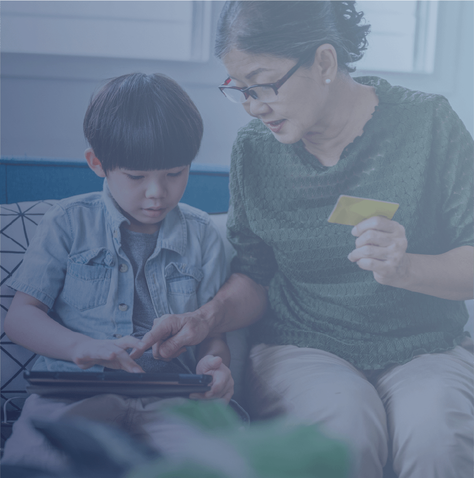 Decorative photo of an elder Asian woman and a young child using a tablet and a credit card