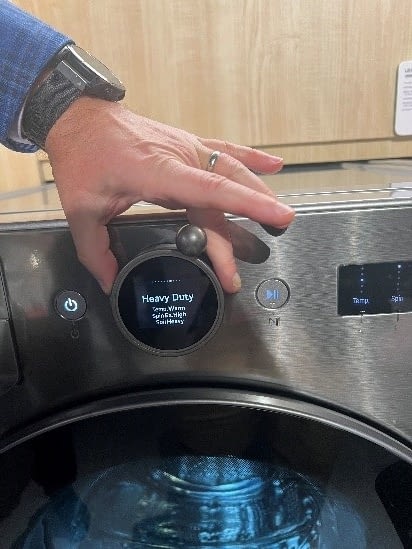 A hand demonstrating the use of a rotatable attachment called the Easy Ball on an LG washer
