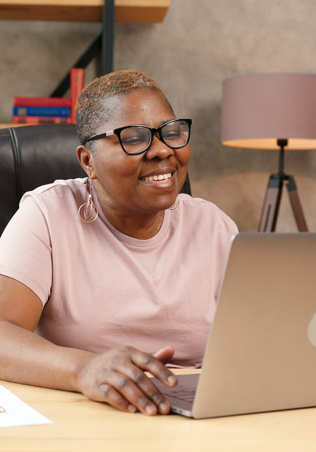 Decorative: a Black woman with a shaved head working on her laptop computer