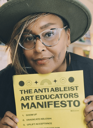 Jen White-Johnson holds up a copy of "The Anti-Ableist Art Educators Manifesto."
