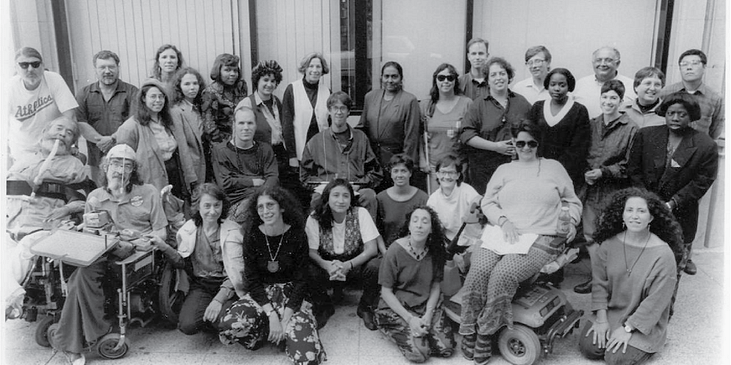 Black and white photo of WID staff of 30 people in the 80s/90s, including Ed and Joan