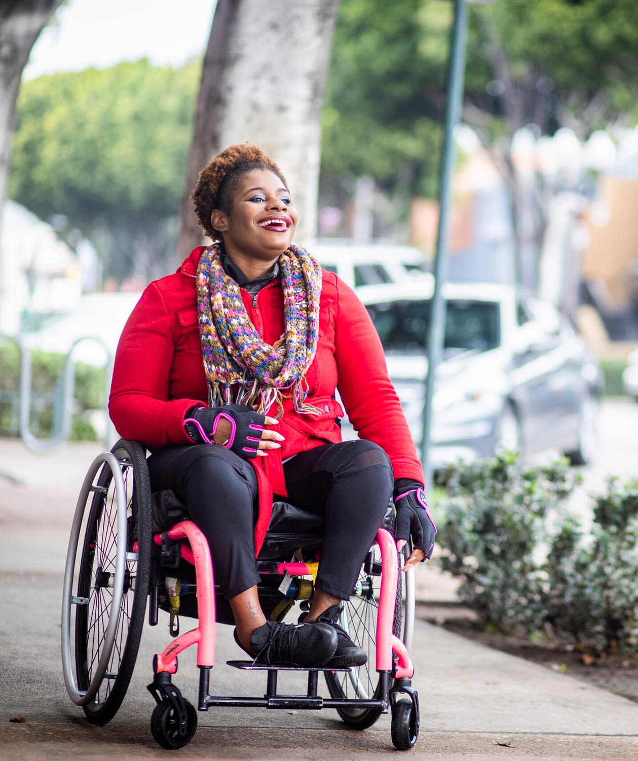 Decorative - A young Black disabled woman with a wheelchair smiling as she rolls down the sidewalk
