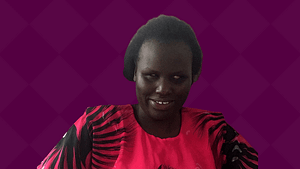 Angeline Akai, a Black woman wearing traditional Kenyan clothing smiles.