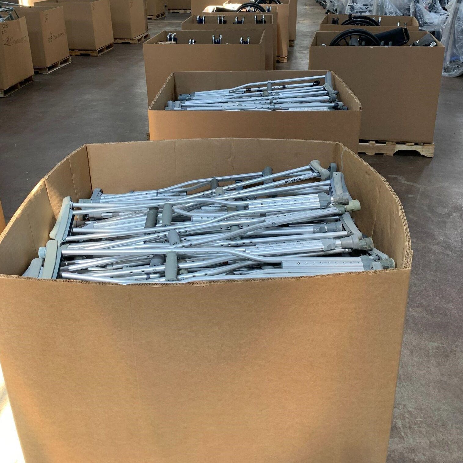 Large cardboard boxes filled with pairs of crutches
