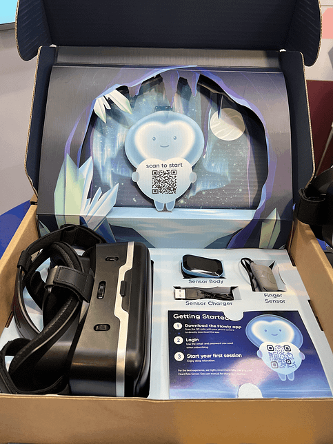 A box with various Flowly materials including the VR headset, a charger, sensor body and finger sensor
