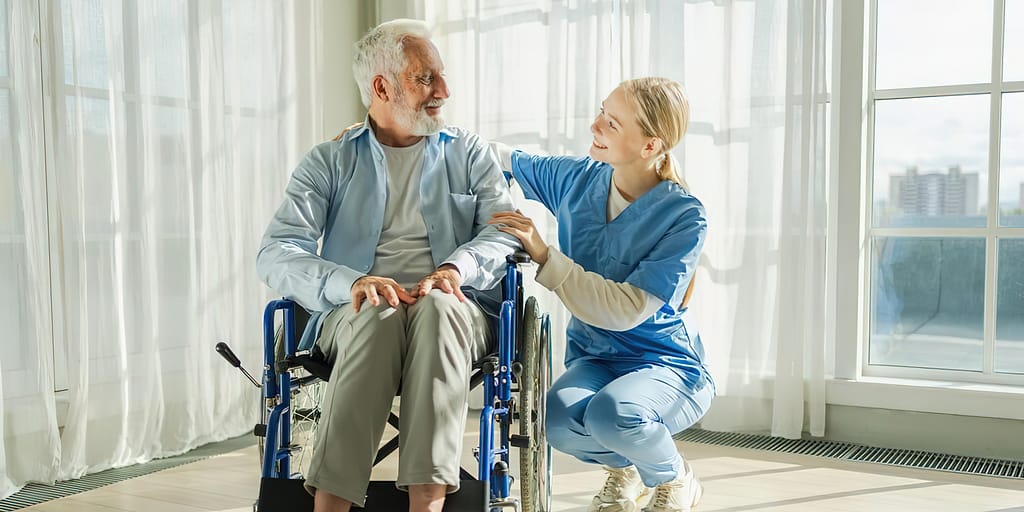 Photo of a man in a wheelchair with a medical provider squatting down beside him