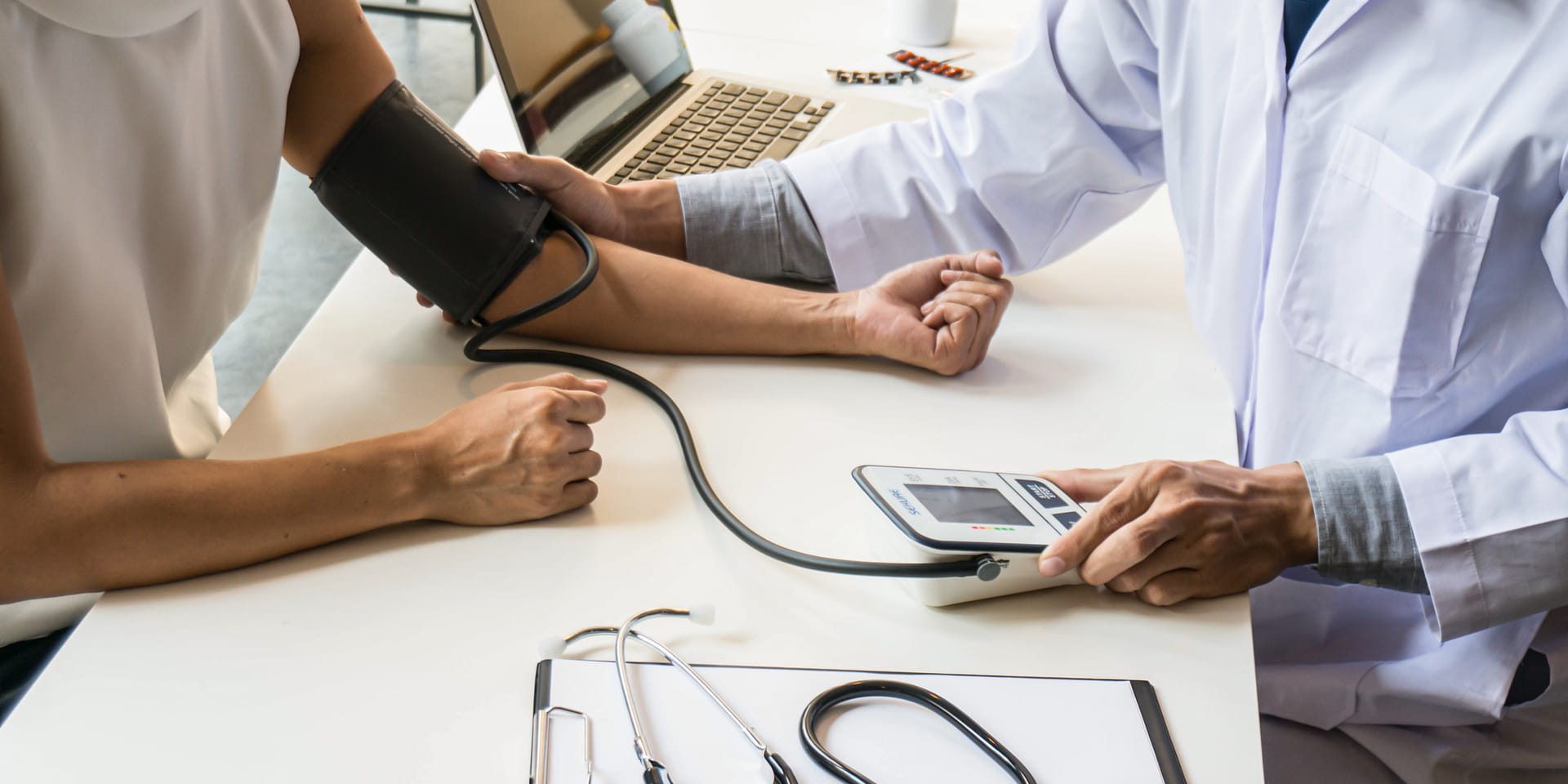 image of medical professional taking blood pressure of an invidivual. Only arms and equipment show.