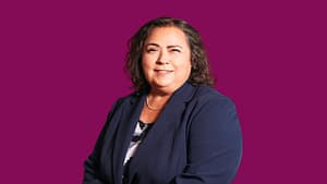Kathy Martinez, a Hispanic, Brown woman wearing a blazer and blouse smiles.
