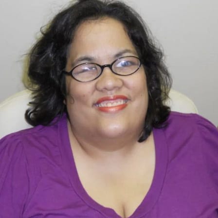 Christina Clift, a woman with a magenta shirt and short black hair smiles.