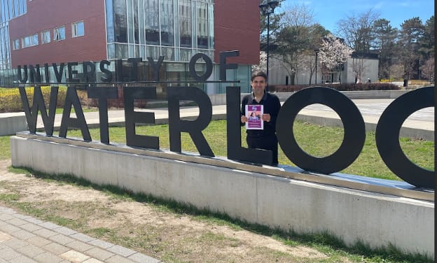 Dr. Munir Sewani standing on the campus of the University of Waterloo campus during a presentation on his Global Heumann Fellowship research