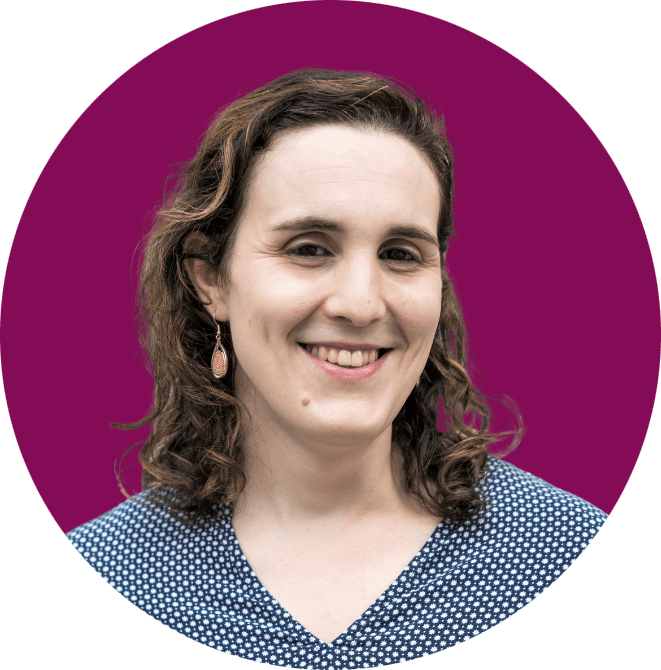 Charlotte Stasio, a white woman with short brown hair smiles while wearing a patterned blouse and earrings.