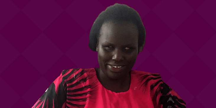 Angeline Akai, a Black woman wearing traditional Kenyan clothing smiles.