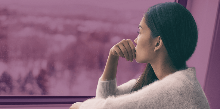 Woman stares outside a window amid a winter storm.