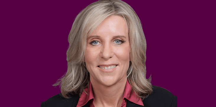 Sheryl Ellis, a white woman wearing a blazer and blouse smiles.