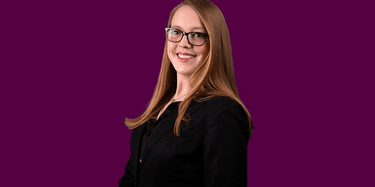 Amy-Francis Smith smiles while wearing eyeglasses and a suit.