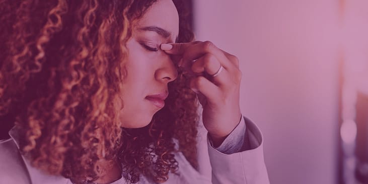 a stressed young woman looks down with her hand on her face