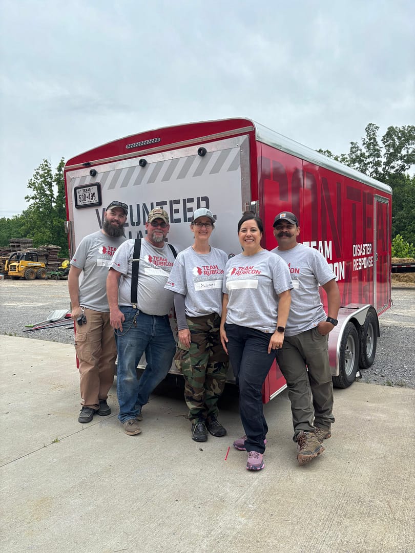 Image_20250529_141803_559 Christina with male and female veterans volunteering with team rubicon in front of a Team Rubicon trailer