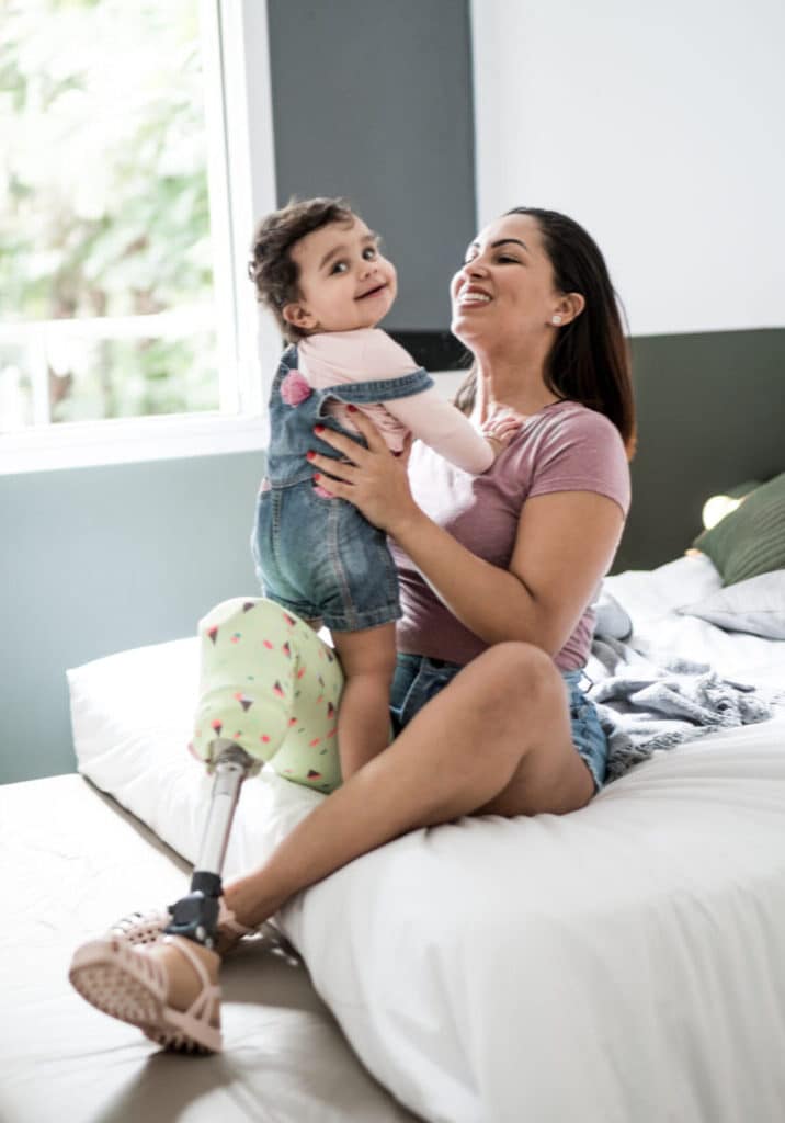 Decorative: A white woman with a prosthetic leg playing with her baby